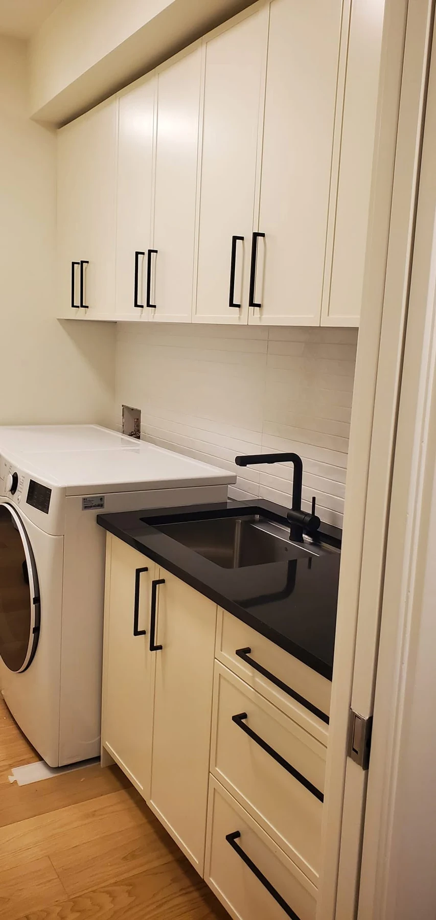 Laundry room with black countertop and white cabinetry